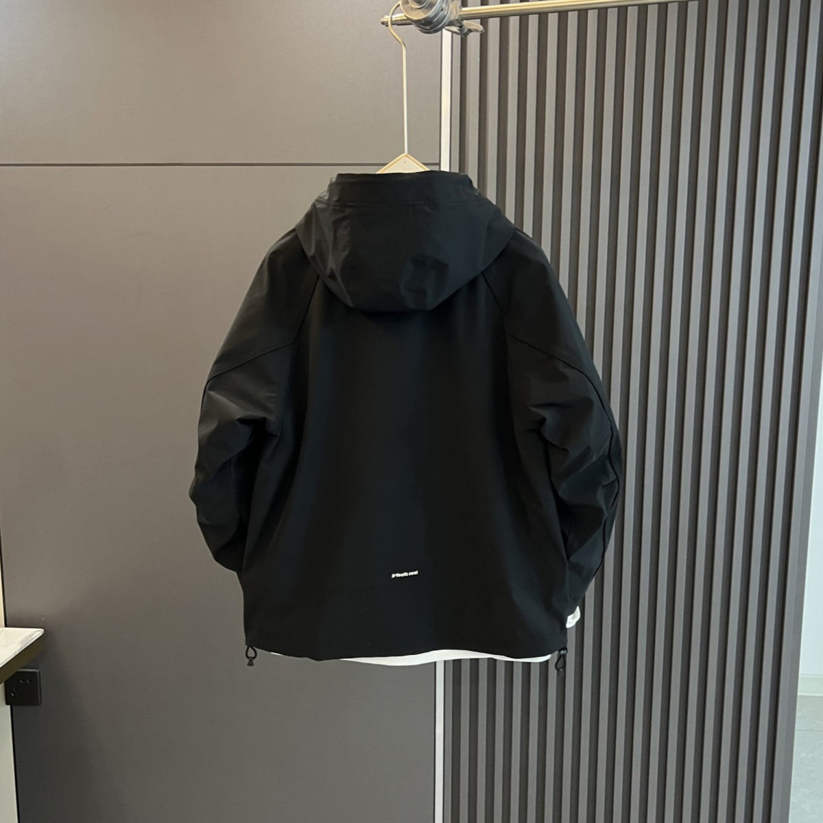 AZUKI Black hooded casual jacket, back view on hanger