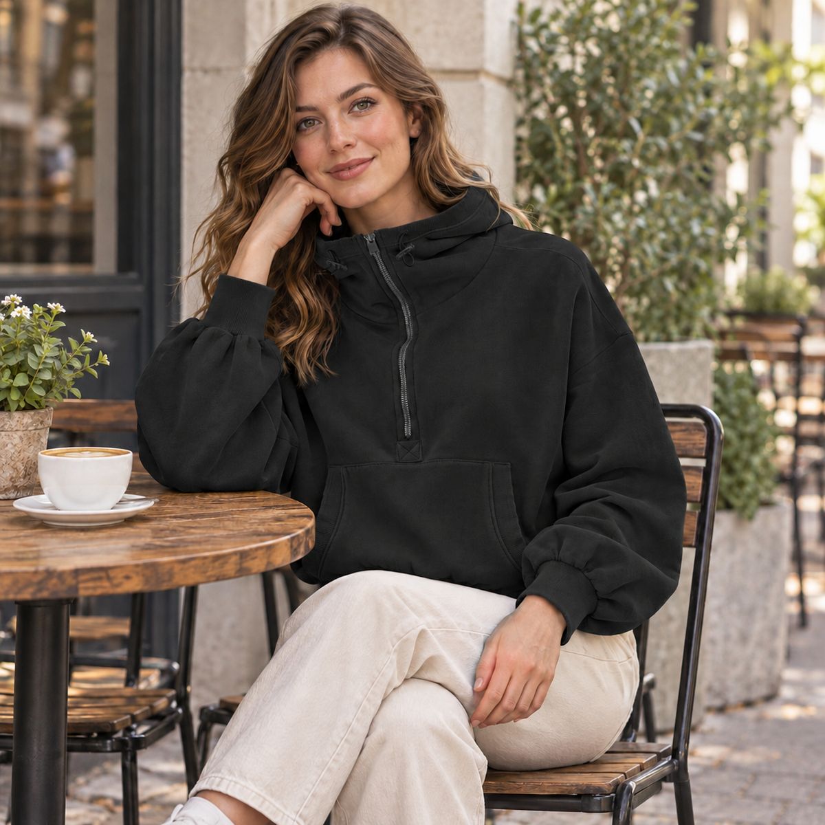 Black relaxed half-zip pullover hoodie, styled at an outdoor cafe