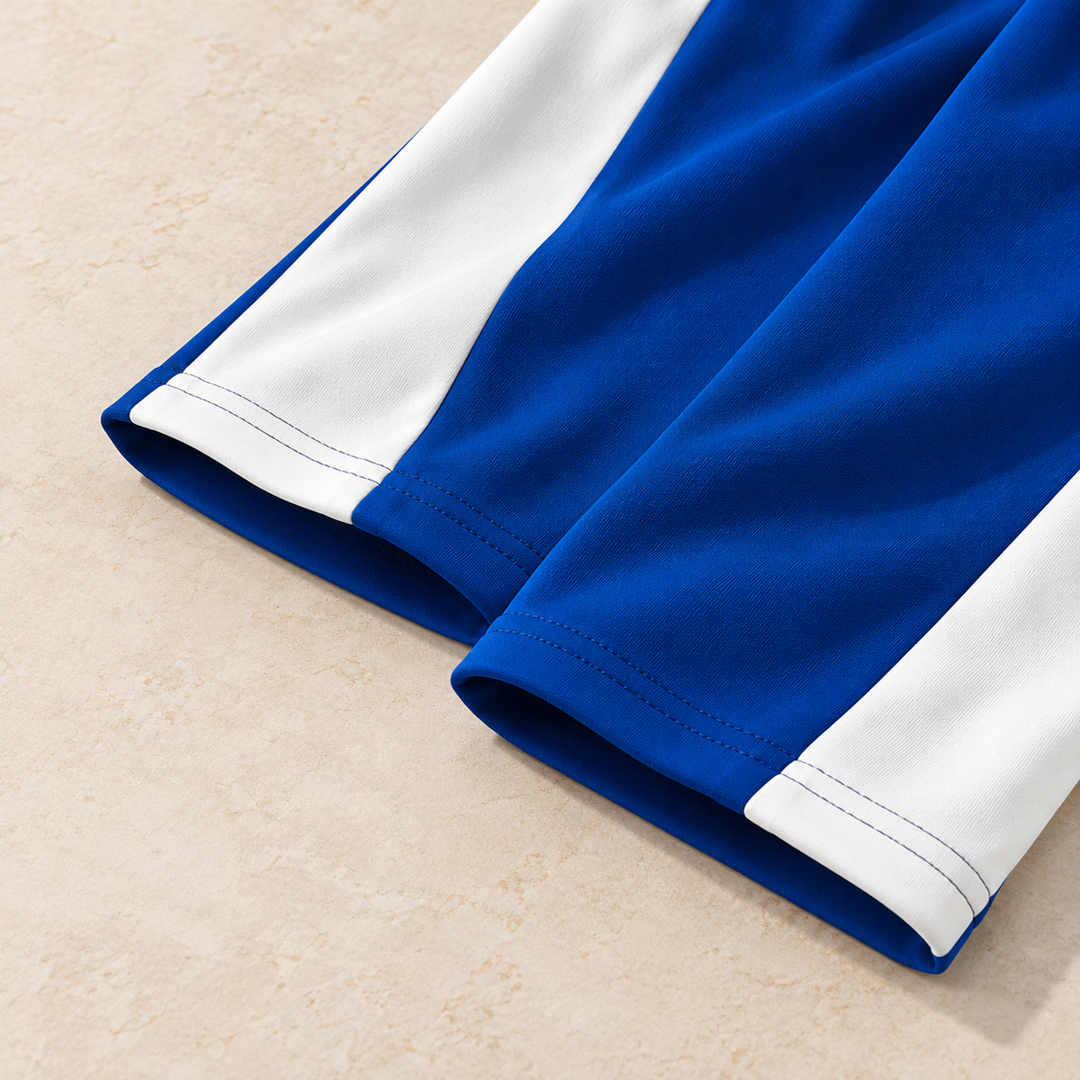 Straight open hems with double stitching on blue and white colorblock pants, detail recreation