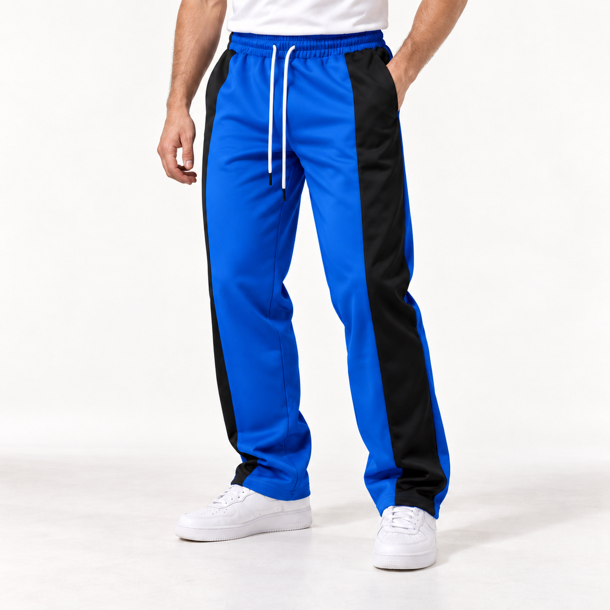 Adult male model wearing blue and black colorblock straight-leg drawstring pants, studio front view