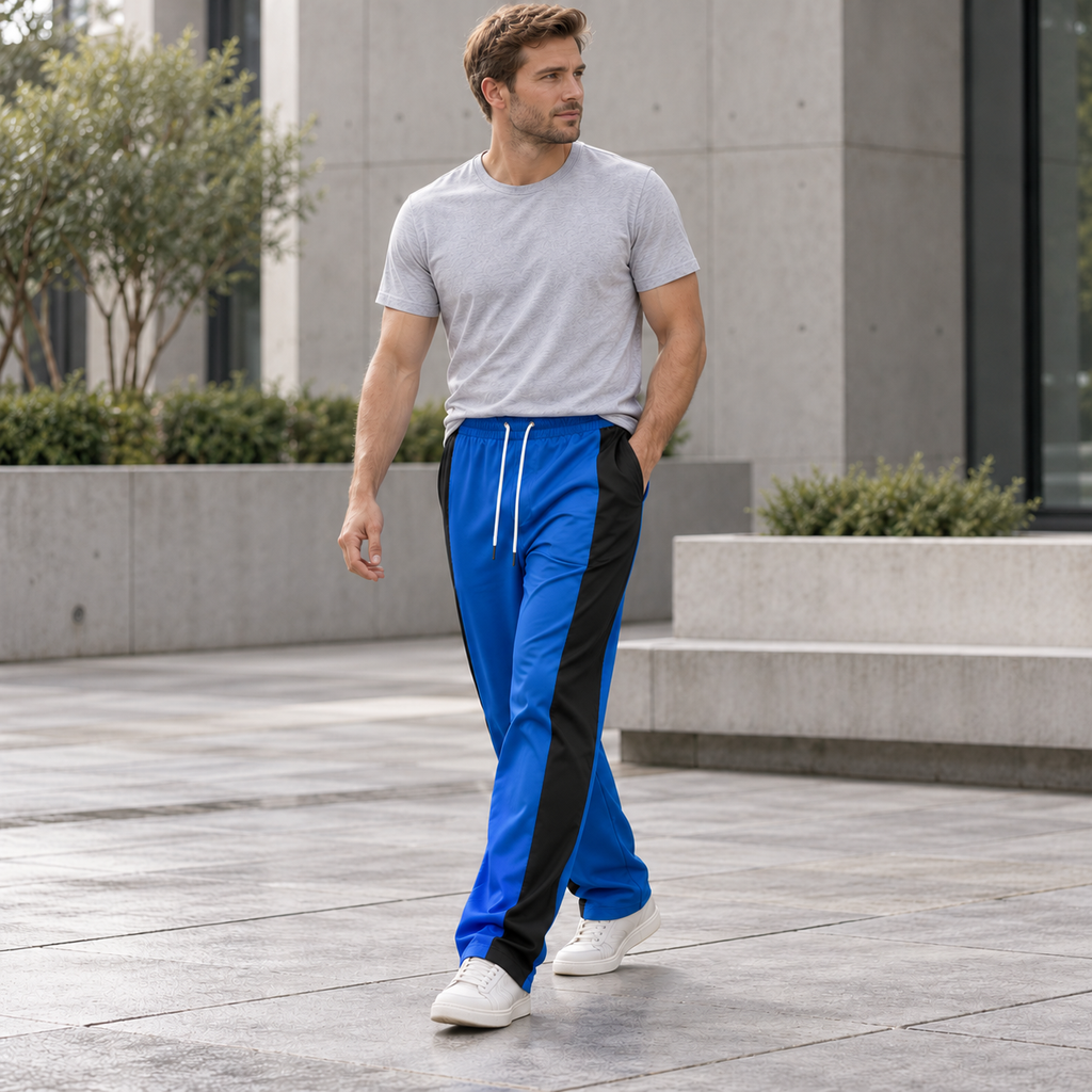 Adult male model wearing blue and black colorblock straight-leg pants in a city courtyard
