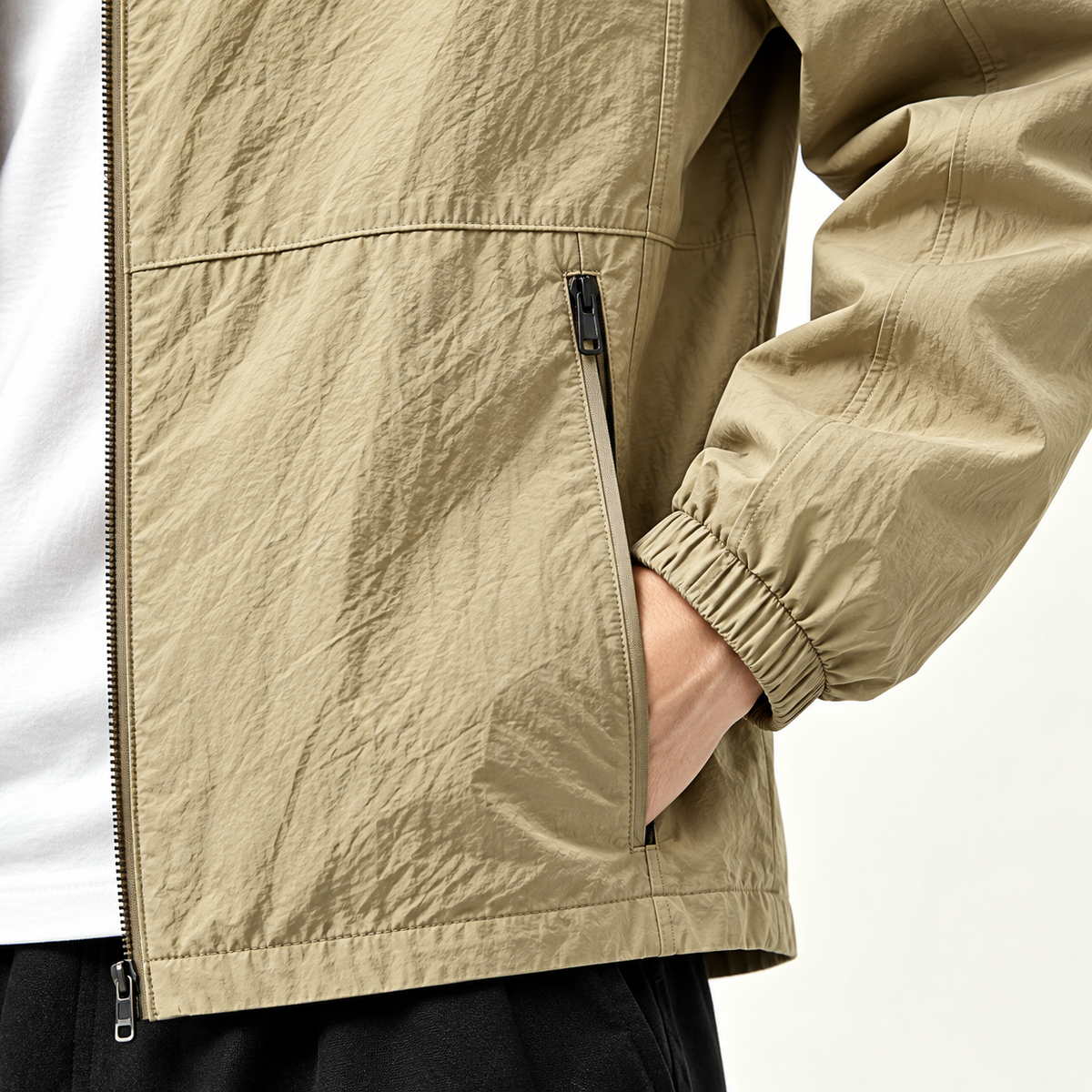 AZUKI khaki stand-collar jacket close-up showing the zip hand pocket, elastic cuff and textured fabric